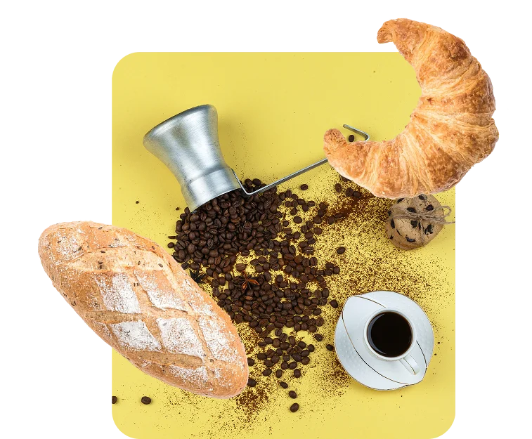 Coffee grinder, croissant, bread and coffee beans on a yellow background